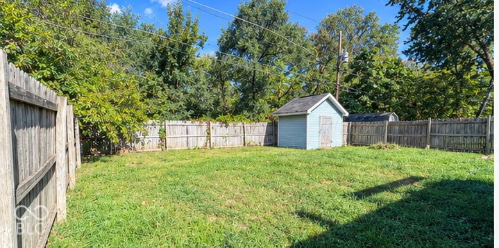 4906 W Troy Avenue, Indianapolis, IN 46241 Private backyard featuring a fenced perimeter, expansive lawn, and detached storage shed
