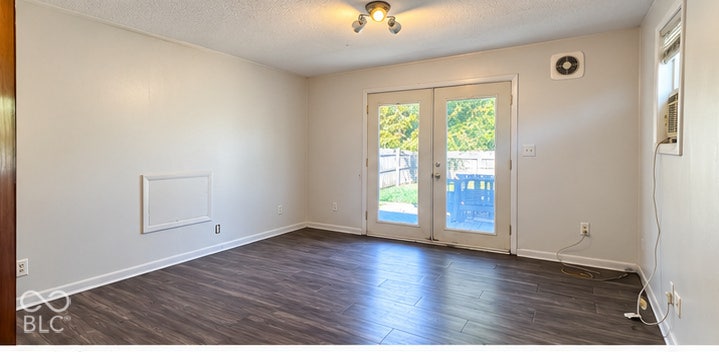 4906 W Troy Avenue, Indianapolis, IN 46241 Room interior featuring wood-finish flooring, glass-paned double doors, a ceiling-mounted light fixture, and neutral-toned wall paint