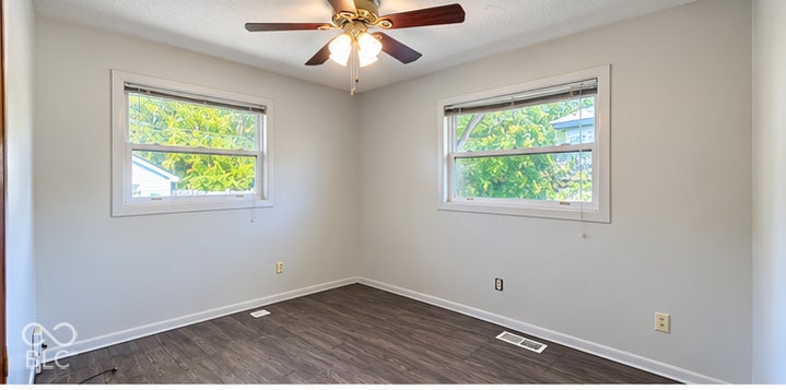 4906 W Troy Avenue, Indianapolis, IN 46241 Room featuring wood-finish flooring, dual windows with white casing, and an integrated multi-blade ceiling fan with light fixture