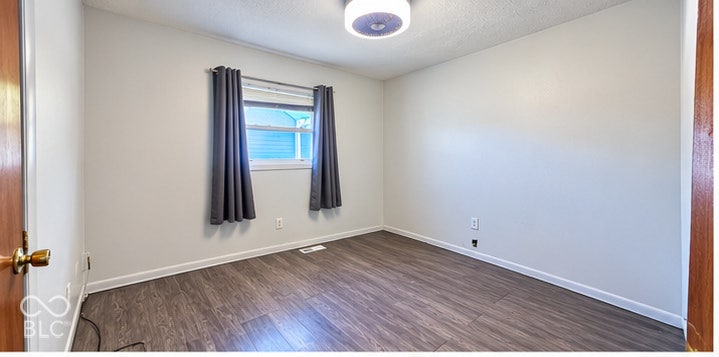 4906 W Troy Avenue, Indianapolis, IN 46241 Interior space featuring wood-finish flooring, neutral wall tones, a single window, and a circular ceiling-mounted light fixture