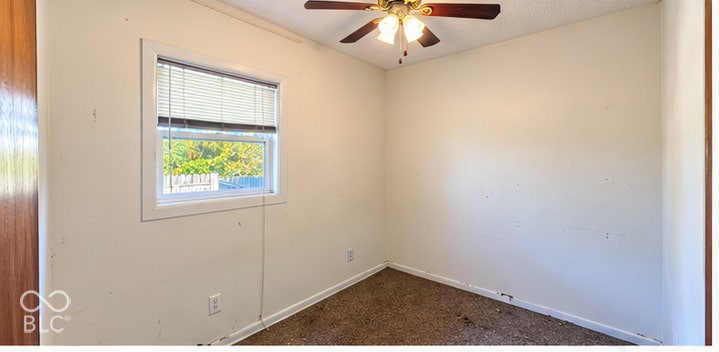 4906 W Troy Avenue, Indianapolis, IN 46241 Room featuring wall-to-wall carpeting, a single-pane window with white trim, and a ceiling-mounted light fixture with a three-blade fan