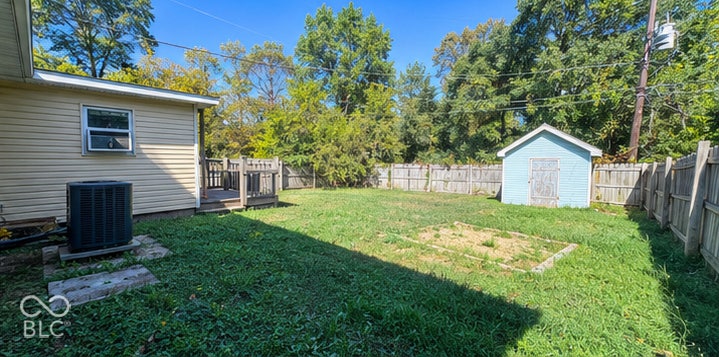 4906 W Troy Avenue, Indianapolis, IN 46241 Fenced backyard featuring a wood deck, detached storage shed, and central garden bed