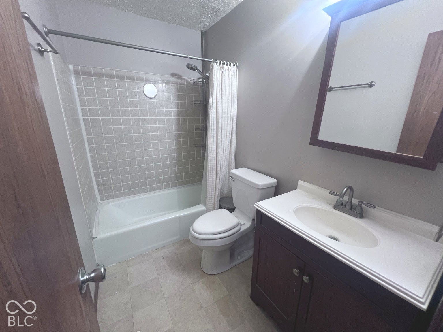 4906 W Troy Avenue, Indianapolis, IN 46241 Bathroom featuring a vanity with an integrated basin, a wood-finish cabinet, a mirrored medicine cabinet, a tiled shower surround, and a tub-shower combination