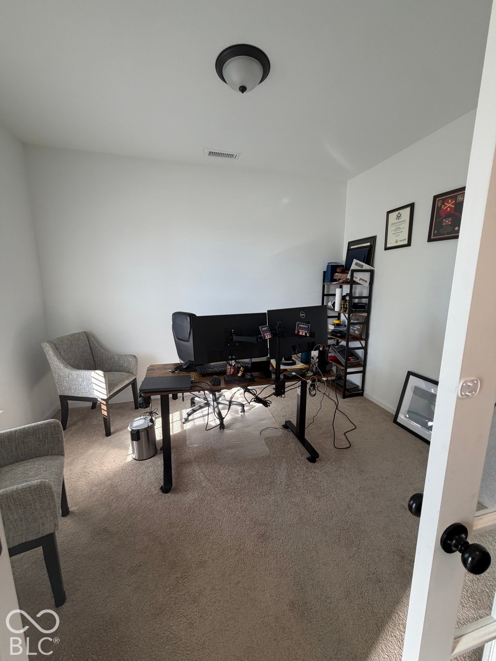 Enclosed room featuring neutral wall-to-wall carpeting, crisp white walls, a flush-mount overhead light fixture, and a white door with matte black hardware
