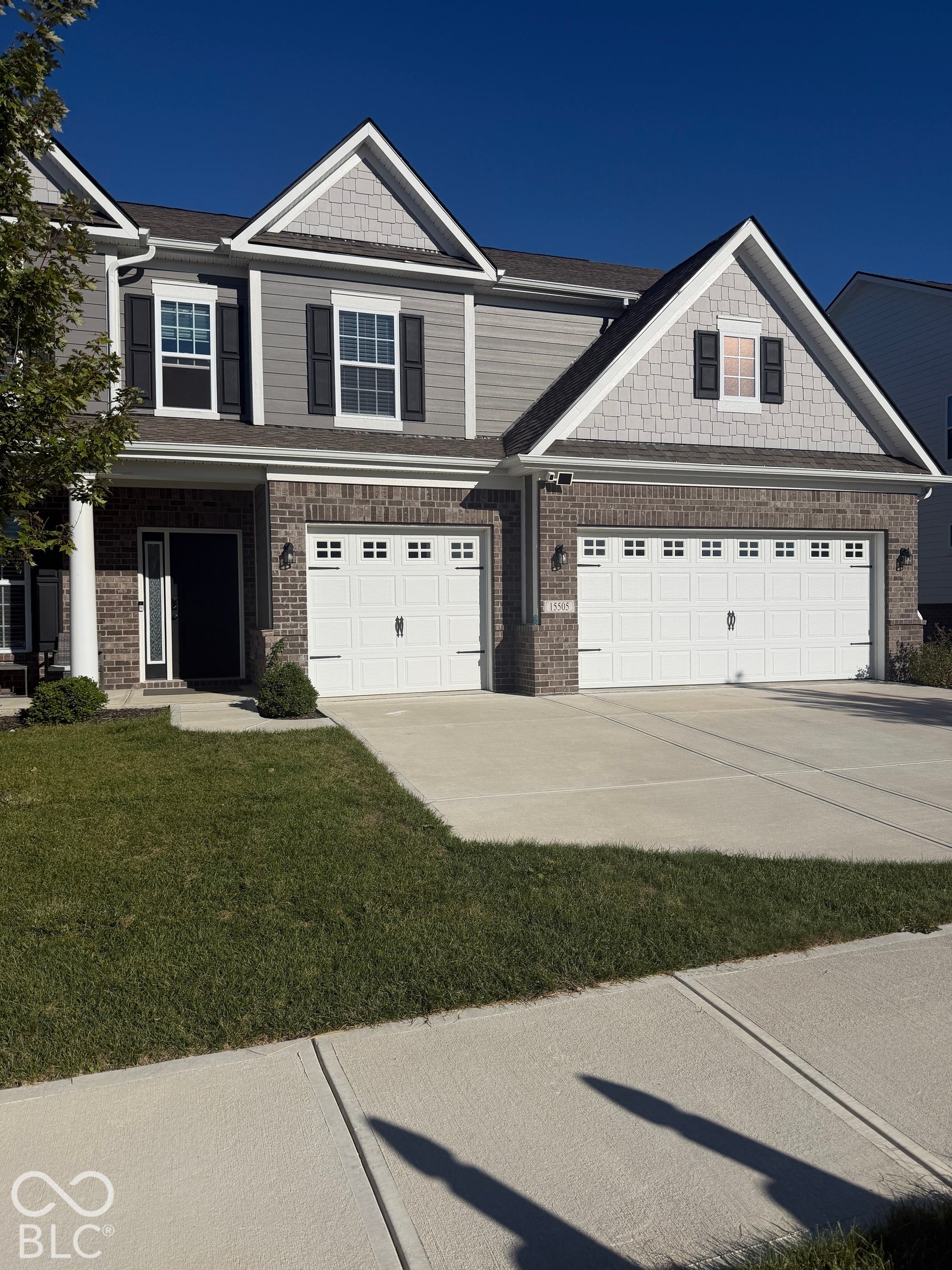 Multi-gable exterior featuring a combination of brick masonry and horizontal lap siding, complemented by a three-car garage and a paved concrete driveway