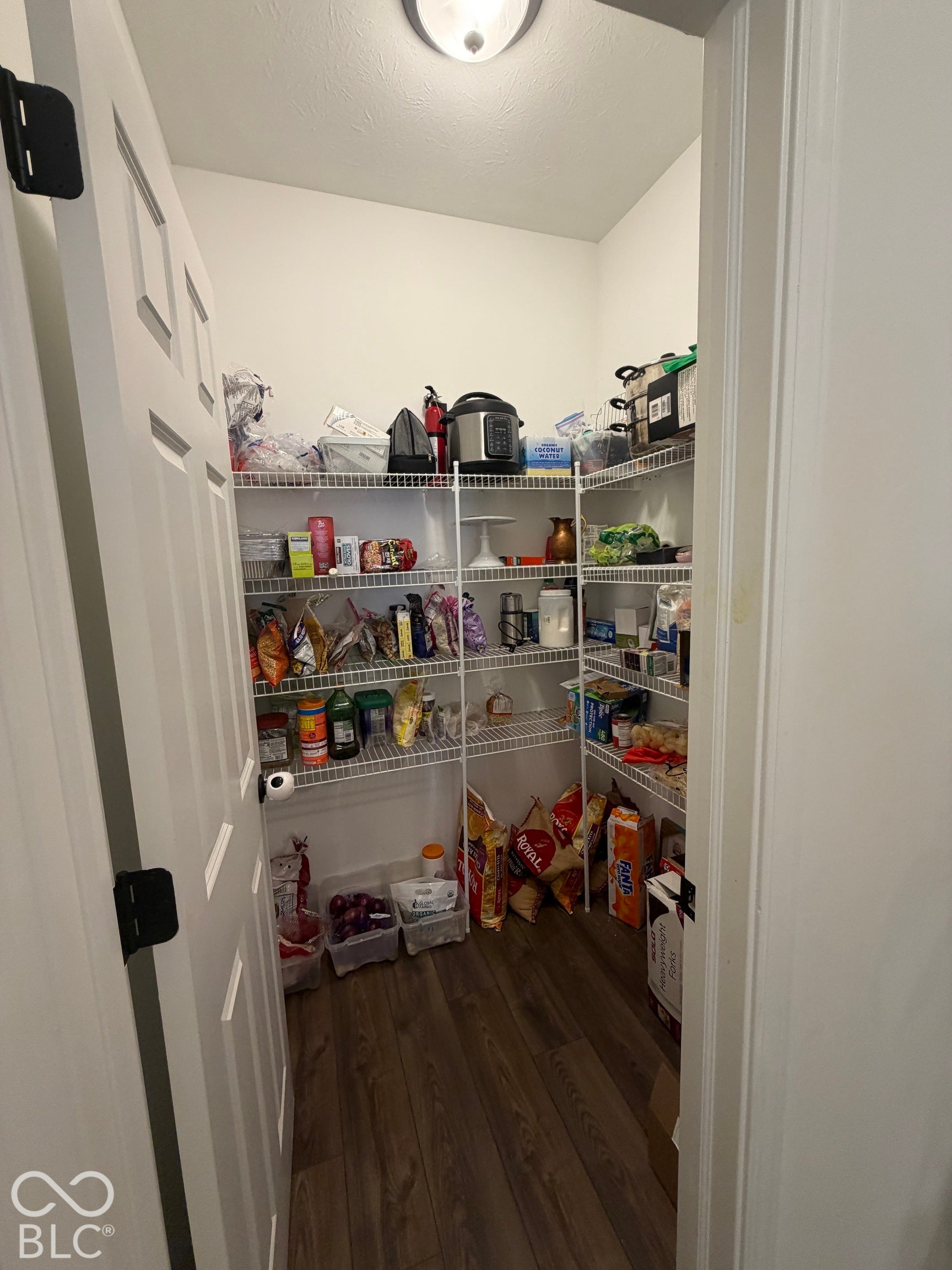 Walk-in pantry featuring white wire shelving and wood-finish flooring