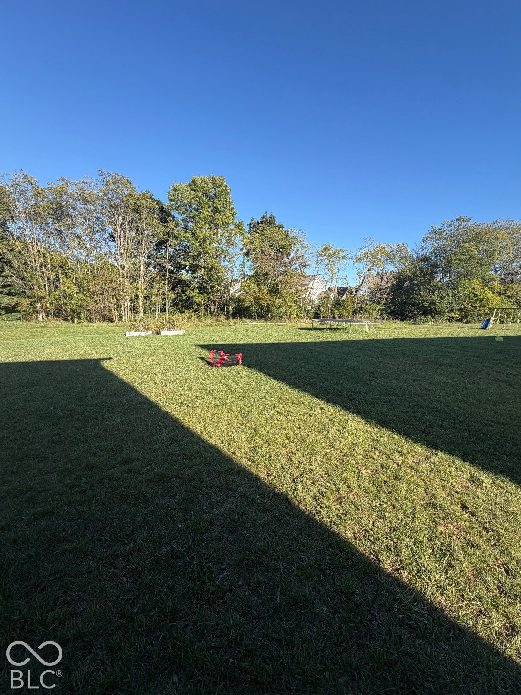 Expansive backyard featuring a large grass lawn and mature perimeter trees