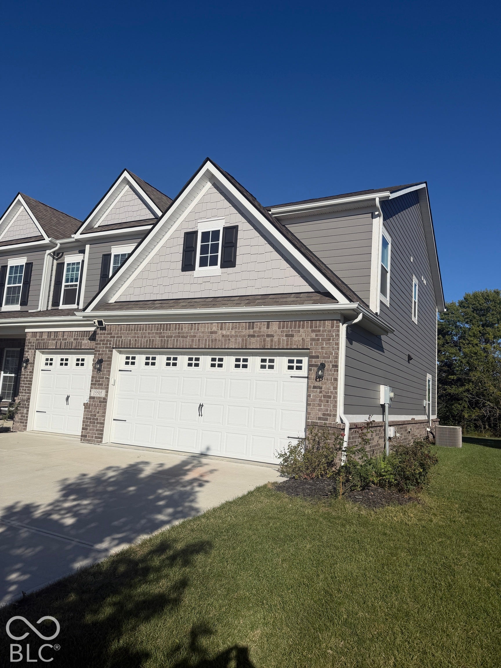 Multi-level exterior featuring brick and siding facade, shingle-style gable accents, two-car garage with carriage-style doors, and decorative shutters