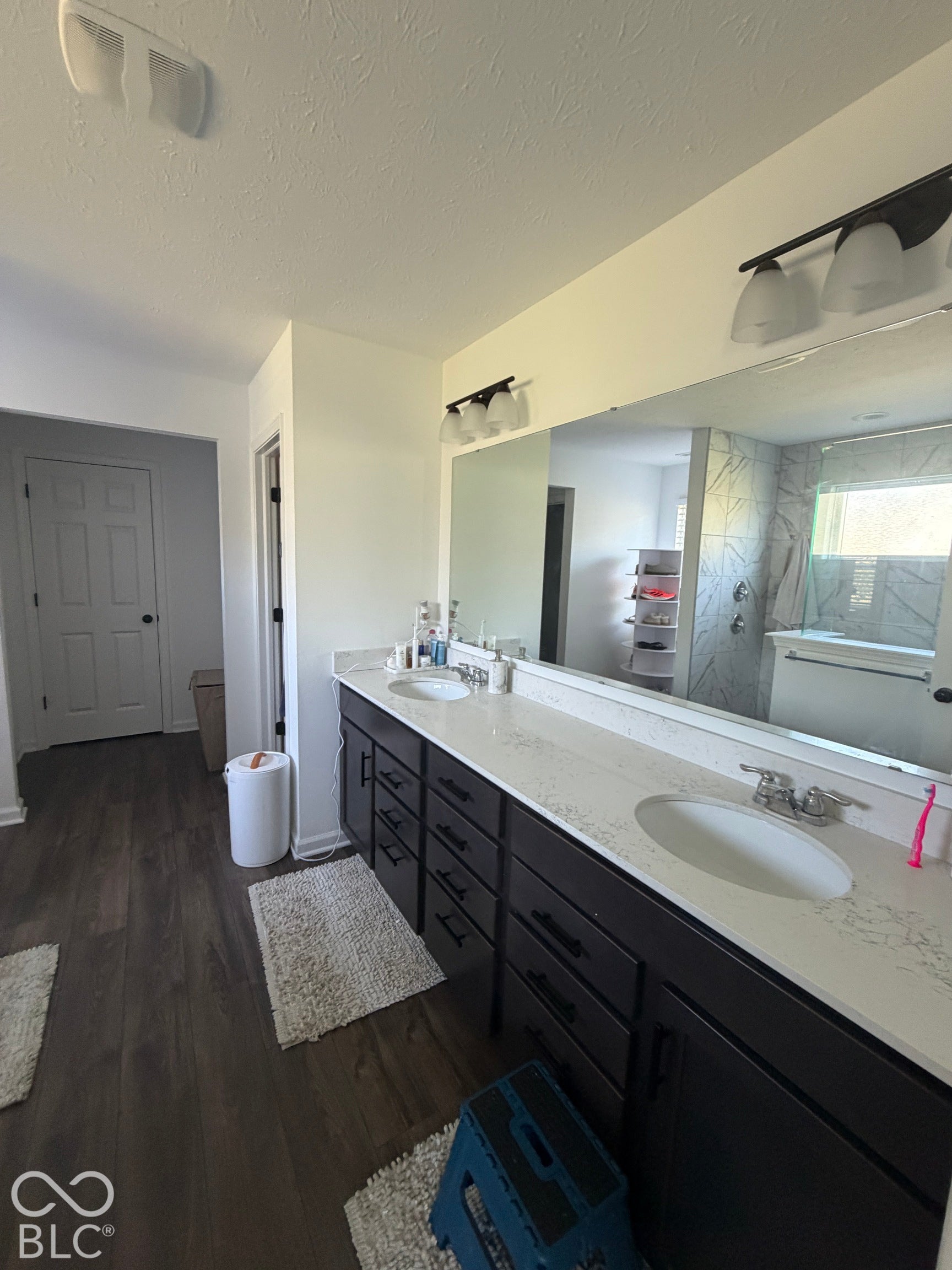 Dual-vanity cabinetry with dark finishes, stone-composite countertops, integrated undermount sinks, and wall-to-wall vanity mirrors