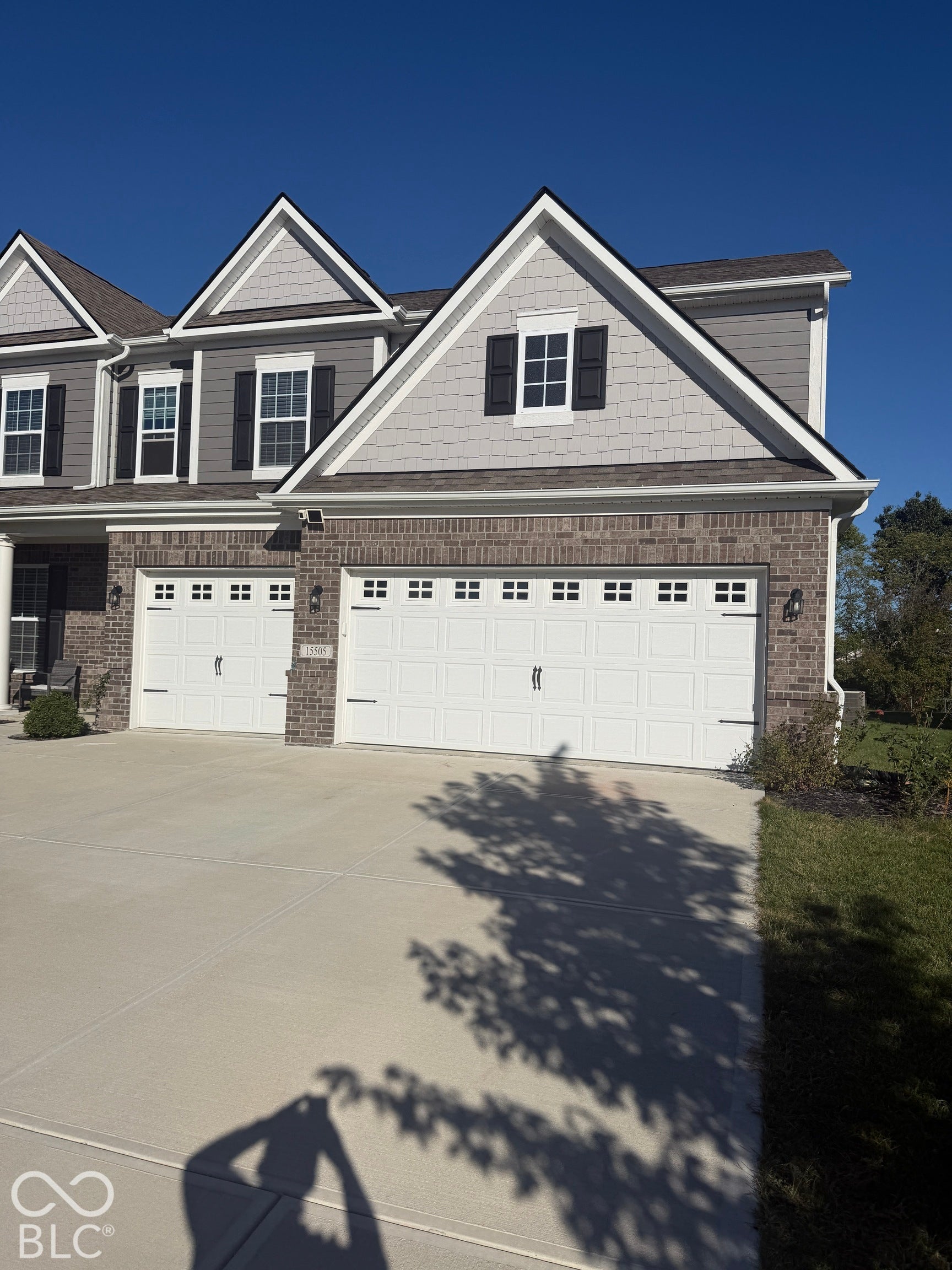 Exterior facade featuring a combination of brick masonry and siding, multi-gabled roofline, three-car garage with paneled doors, and shake-style siding accents