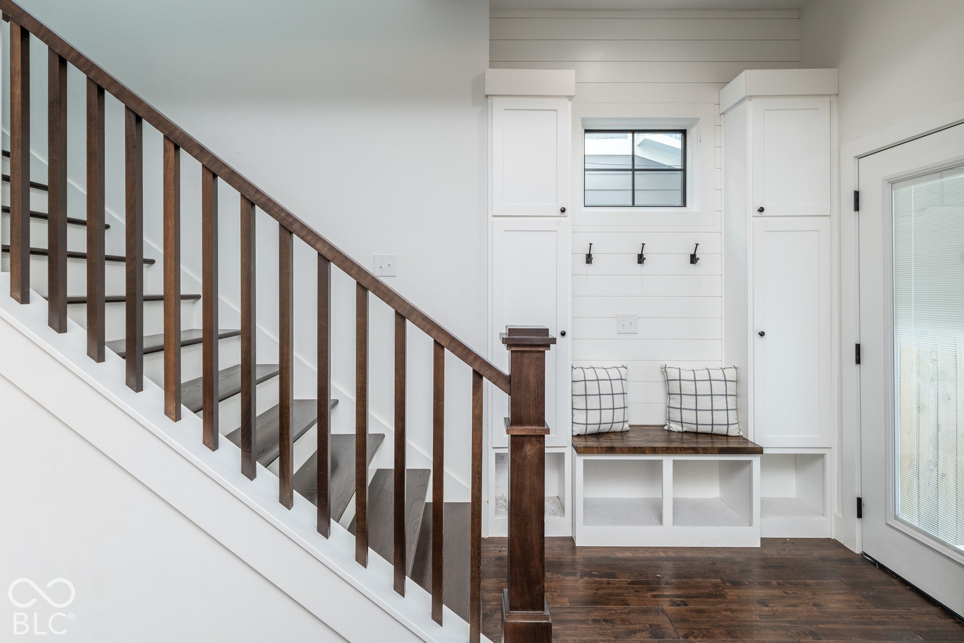 1401 Olive Street, Indianapolis, IN 46203 Staircase featuring a dark wood-finish handrail and treads, integrated white cabinetry with shiplap detailing, a built-in bench with a wood-finish surface, and matte black hardware