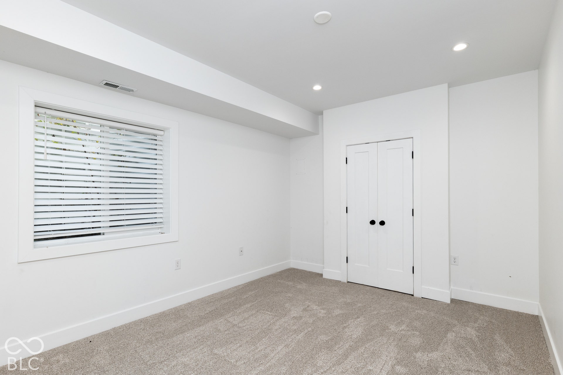 1401 Olive Street, Indianapolis, IN 46203 Neutral-toned carpeting, recessed ceiling lighting, and a double-door closet with matte black hardware, featuring a window with horizontal blinds