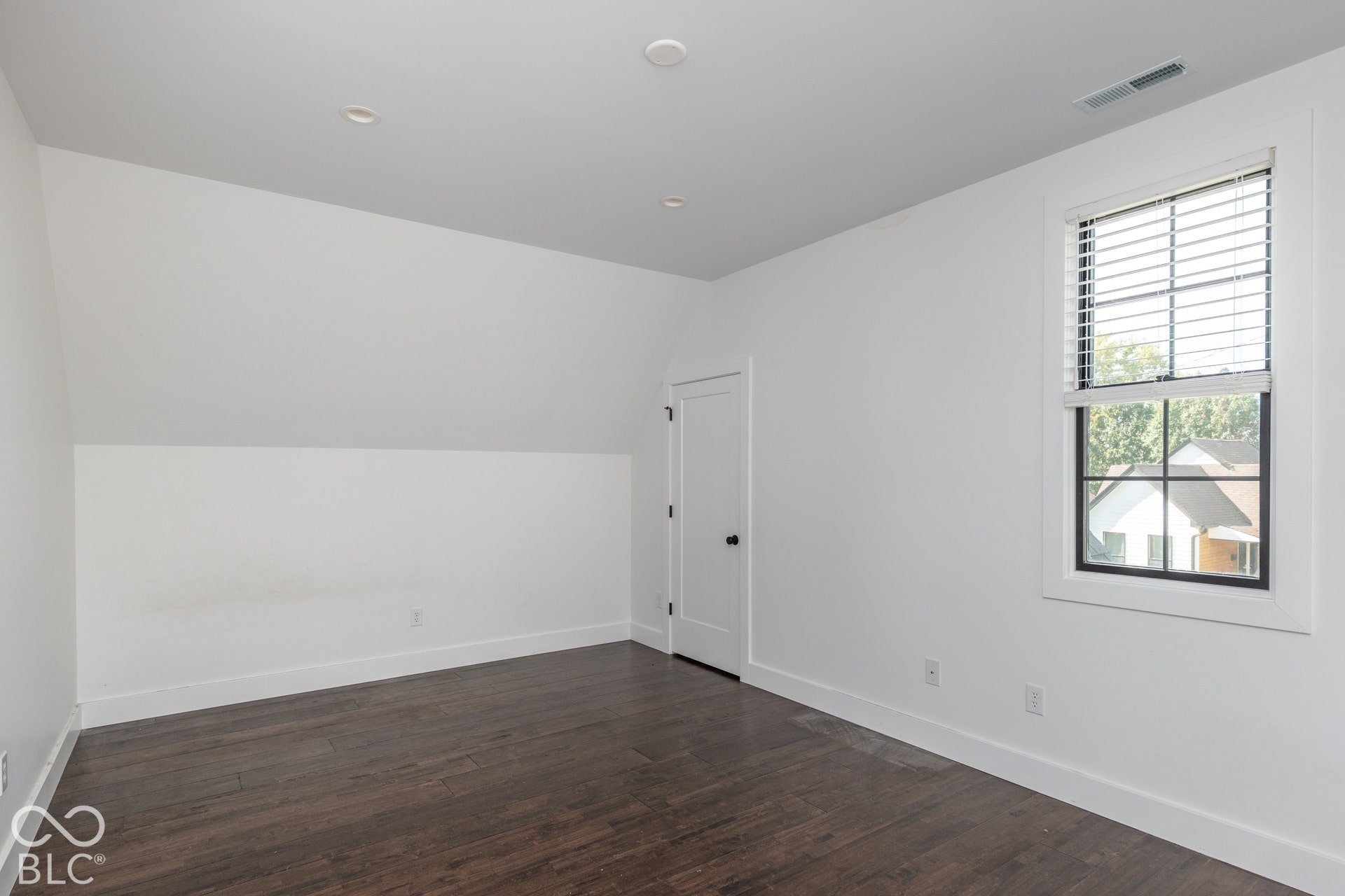 1401 Olive Street, Indianapolis, IN 46203 Room featuring wood-finish flooring, recessed lighting, slanted ceiling detail, a single-panel interior door, and a multi-pane window with dark trim