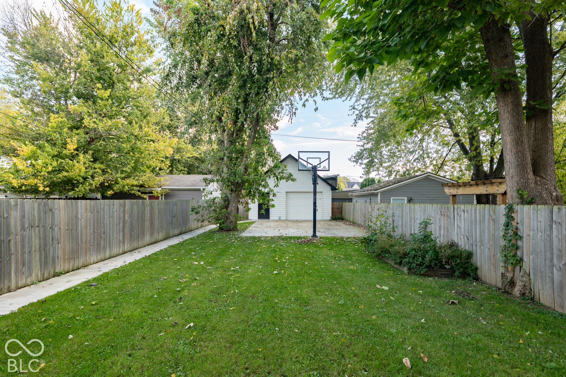 1401 Olive Street, Indianapolis, IN 46203 Fenced backyard featuring a manicured lawn, concrete patio, detached garage, and mature trees