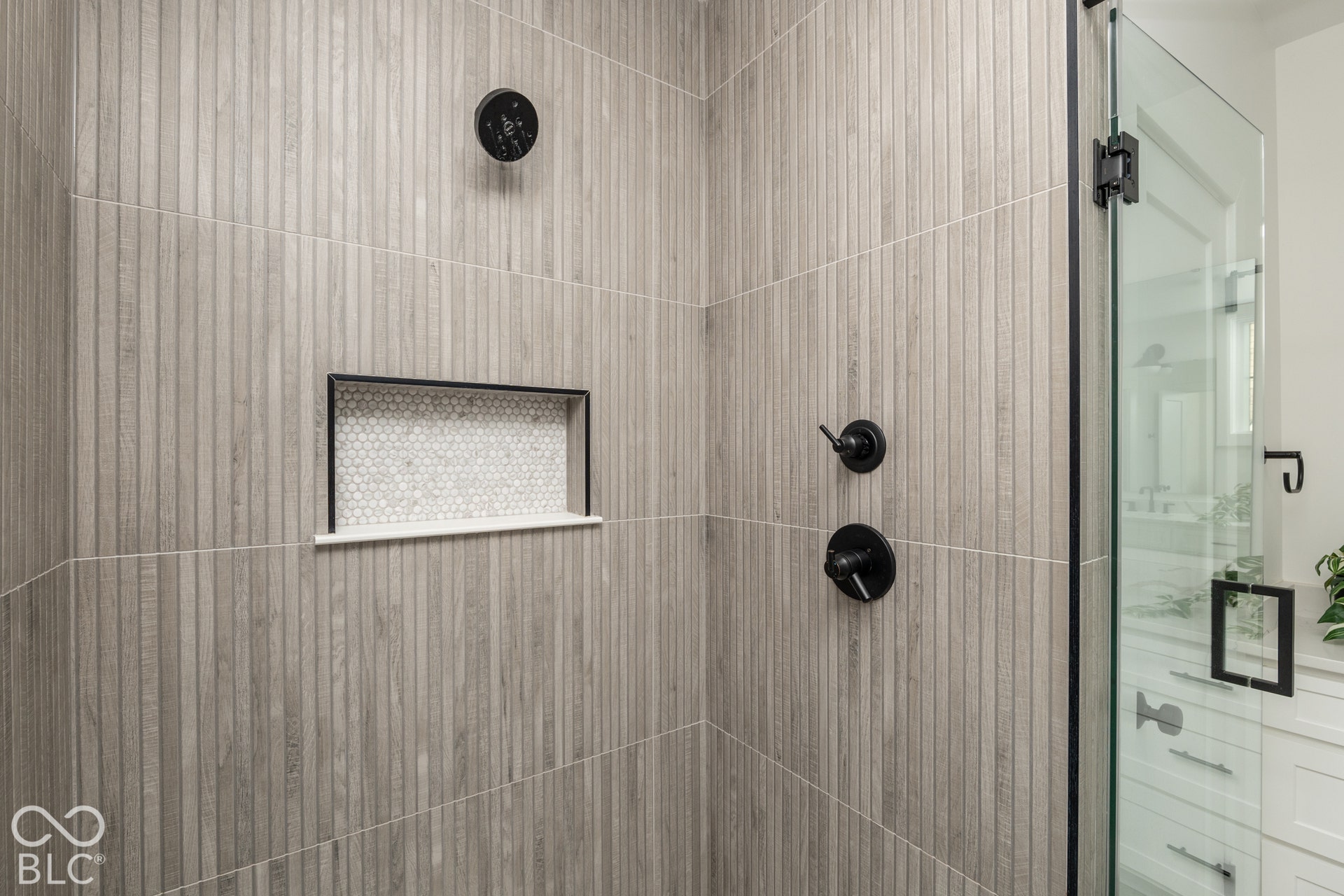 1401 Olive Street, Indianapolis, IN 46203 Walk-in shower featuring vertical textured wall tile, built-in recessed niche with mosaic tiling, matte black plumbing fixtures, and a frameless glass enclosure
