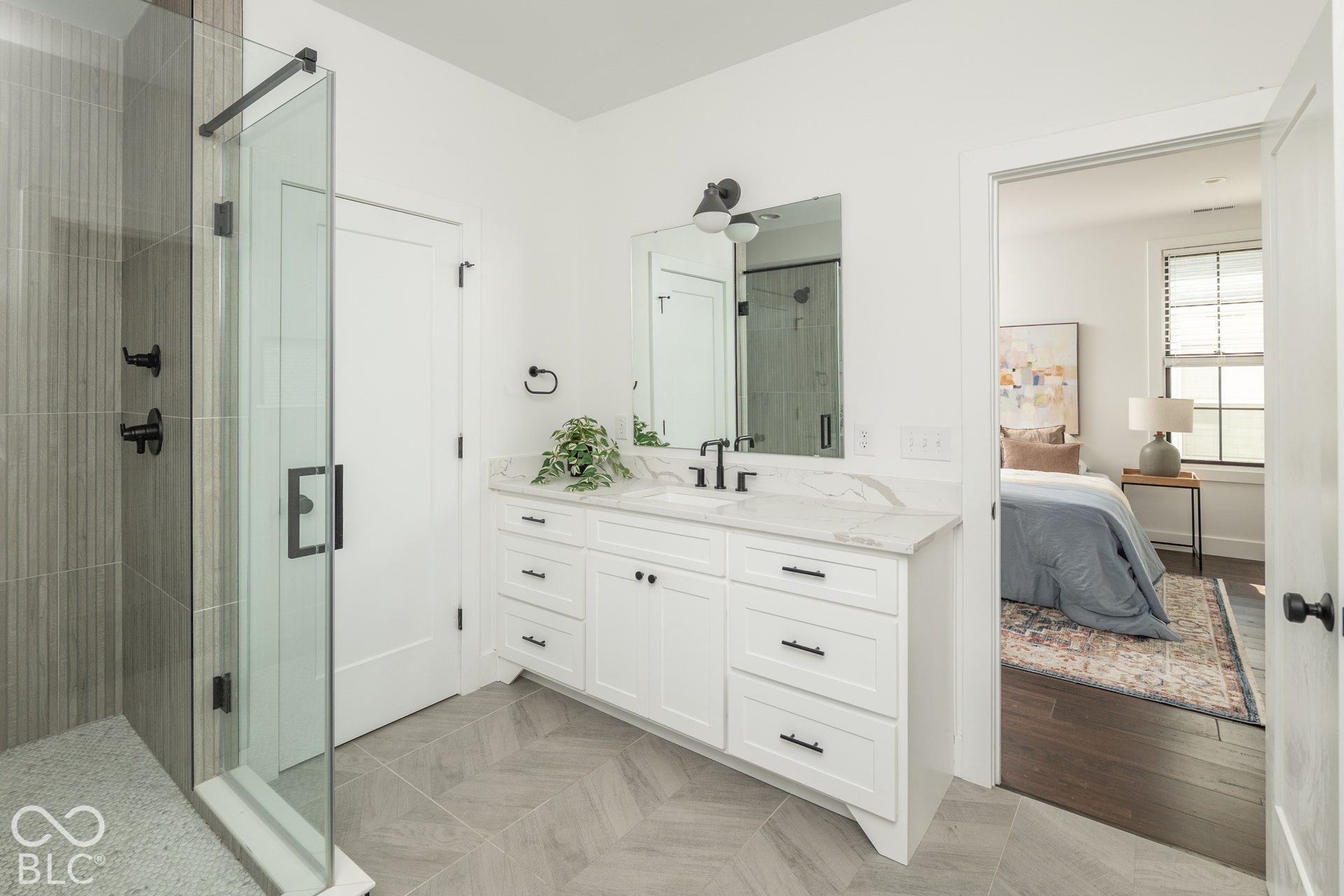 1401 Olive Street, Indianapolis, IN 46203 Bathroom featuring a white shaker-style vanity with stone-finish countertop, walk-in shower with floor-to-ceiling tile, matte black fixtures, and herringbone-pattern tile flooring