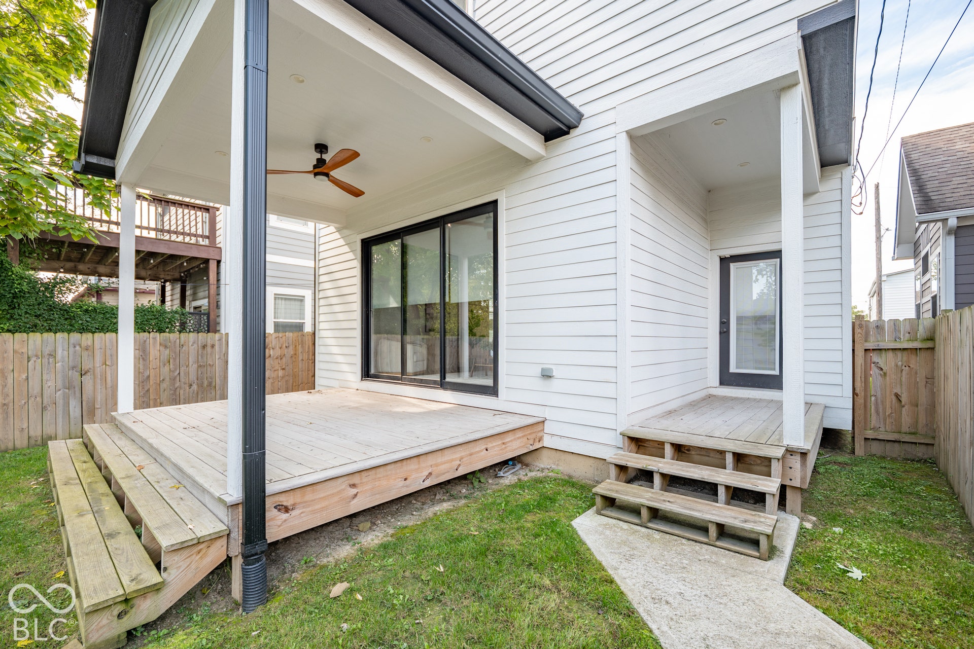 1401 Olive Street, Indianapolis, IN 46203 Covered rear deck with ceiling fan, white horizontal siding, dual-level wood decking, sliding glass doors, and recessed exterior lighting