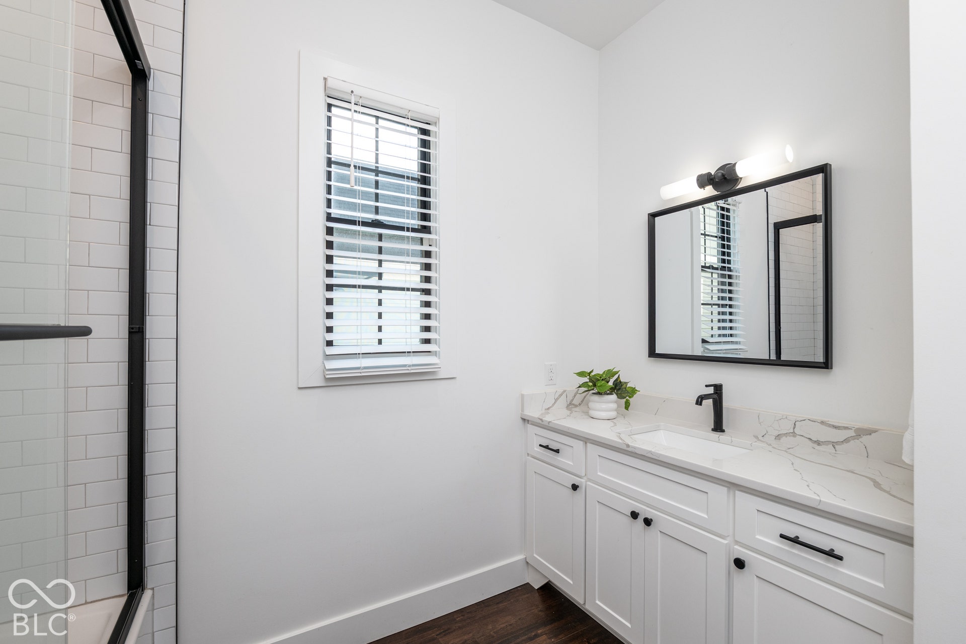 1401 Olive Street, Indianapolis, IN 46203 White shaker-style cabinetry with stone-patterned countertop, integrated undermount sink, matte black hardware, and wood-finish flooring