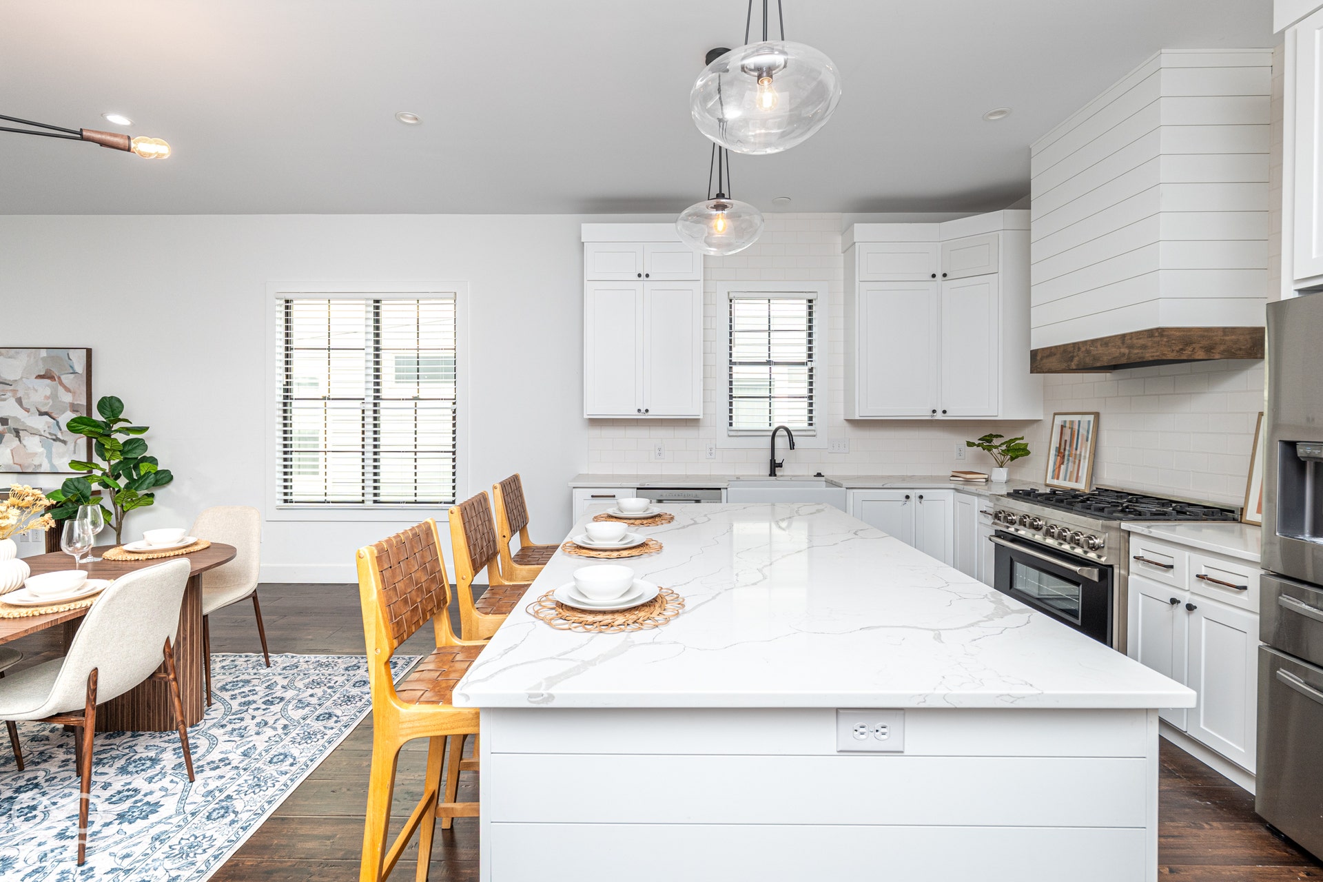 1401 Olive Street, Indianapolis, IN 46203 Kitchen featuring a large central island with light-toned stone surfacing, white shaker-style cabinetry, a custom shiplap range hood with a natural wood trim, farmhouse-style sink, and glass pendant lighting