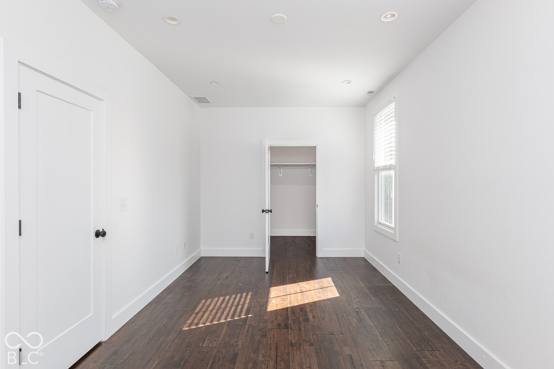 1401 Olive Street, Indianapolis, IN 46203 Room featuring dark wood-finish flooring, recessed ceiling lighting, a single-panel interior door, and a reach-in closet with built-in shelving