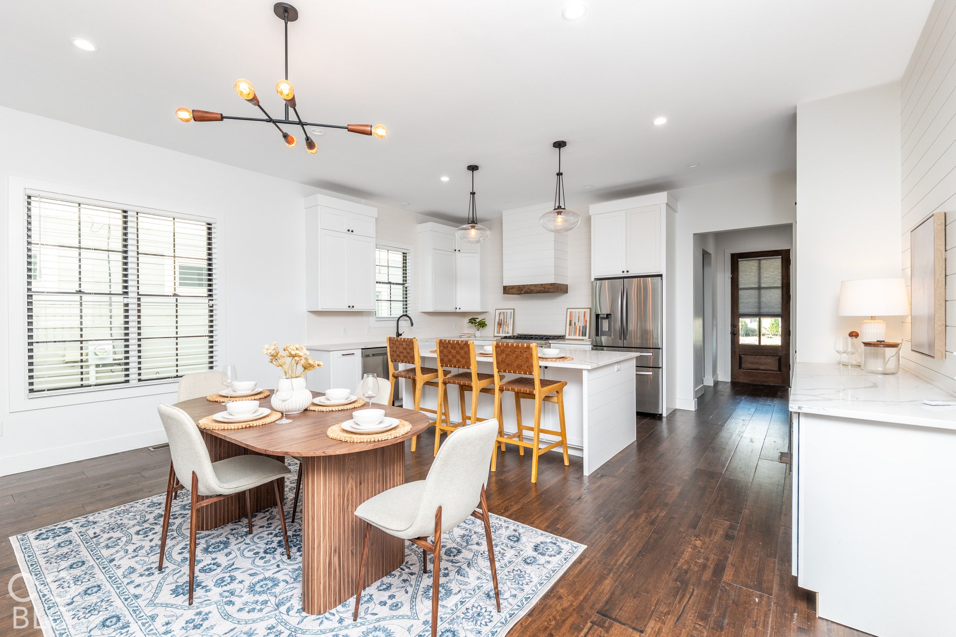 1401 Olive Street, Indianapolis, IN 46203 Kitchen featuring wood-finish flooring, a central island with countertop seating, custom white cabinetry, pendant lighting, and a neutral shiplap wall accent
