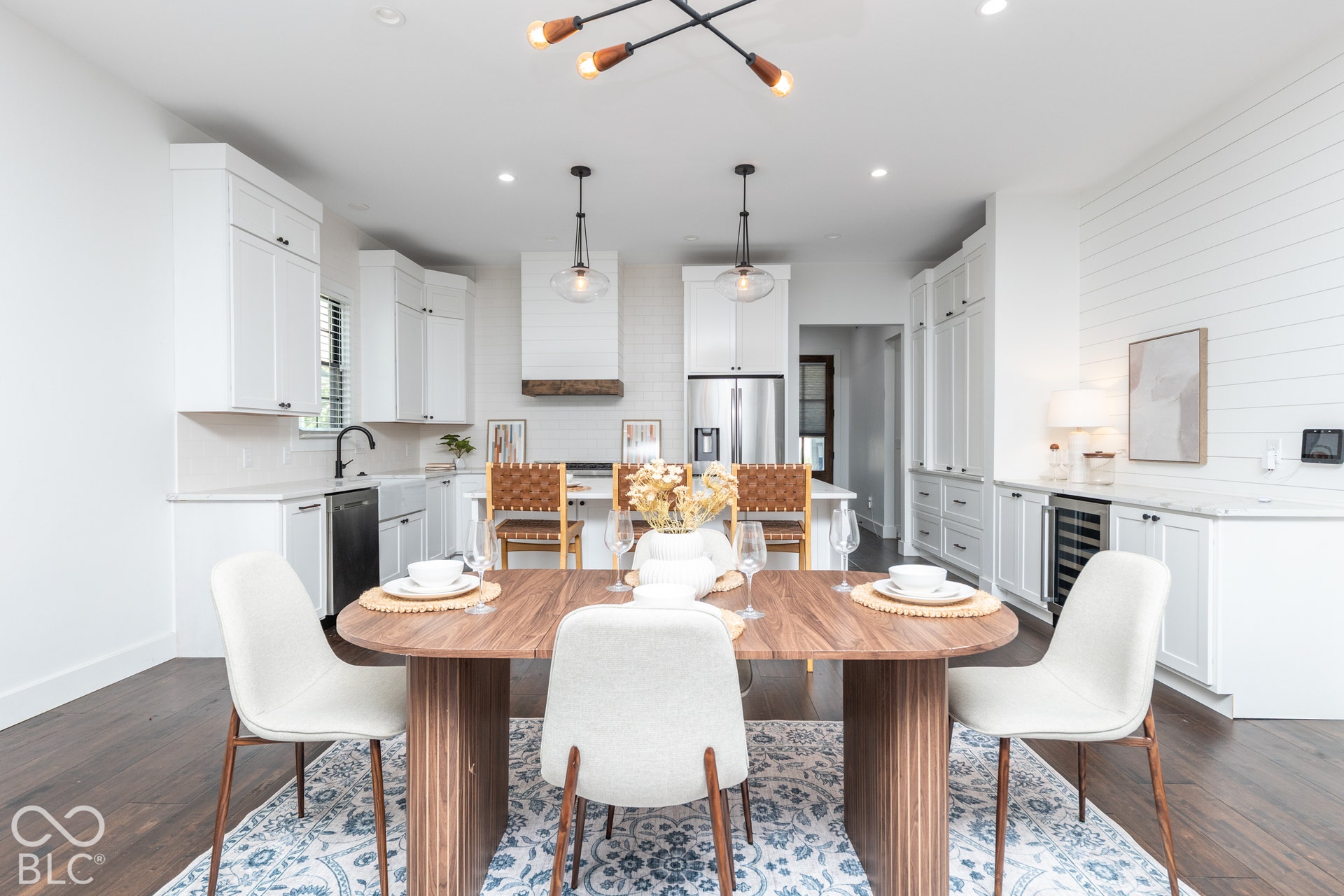 1401 Olive Street, Indianapolis, IN 46203 Kitchen featuring white shaker-style cabinetry, a wood-accented range hood, quartz countertops, a farmhouse sink, and shiplap wall detailing