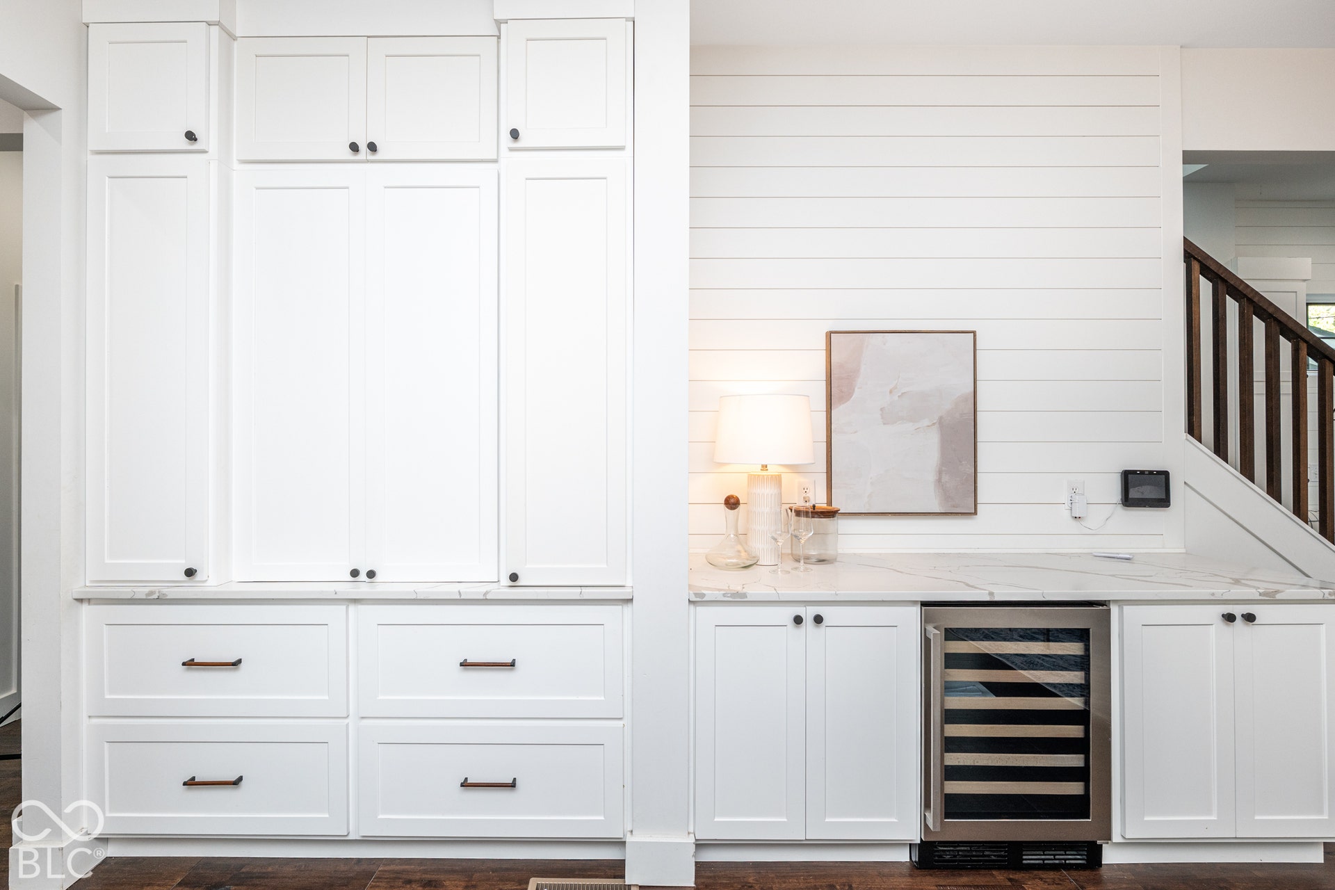 1401 Olive Street, Indianapolis, IN 46203 Custom floor-to-ceiling white cabinetry, integrated beverage refrigerator, stone-surface countertop, horizontal shiplap wall paneling, and dark wood-finish flooring