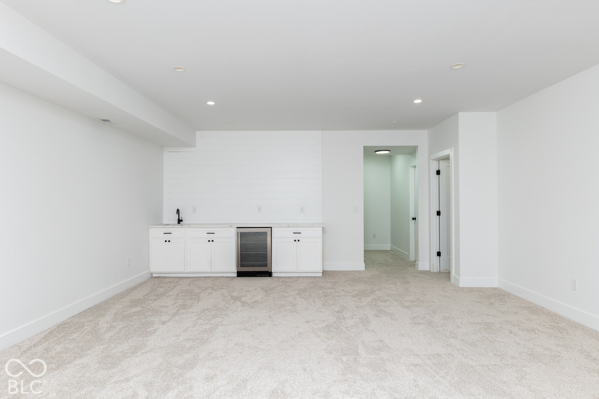 1401 Olive Street, Indianapolis, IN 46203 Wet bar featuring white shaker-style cabinetry, horizontal shiplap backsplash, stone countertop, undermount sink with a matte black faucet, and an integrated beverage refrigerator