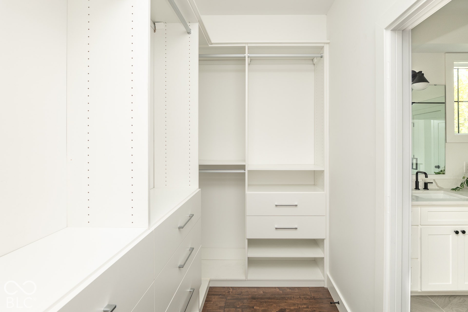 1401 Olive Street, Indianapolis, IN 46203 Walk-in closet featuring white built-in shelving, multiple pull-out drawers with metallic hardware, dual hanging rods, and wood-finish flooring