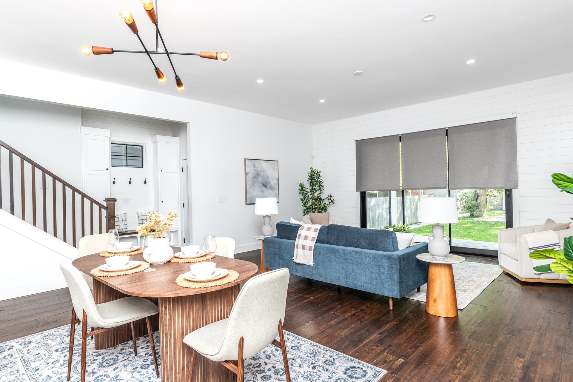 1401 Olive Street, Indianapolis, IN 46203 Open-concept interior featuring wood-finish flooring, horizontal shiplap wall detailing, a multi-arm modern light fixture, and large sliding glass doors