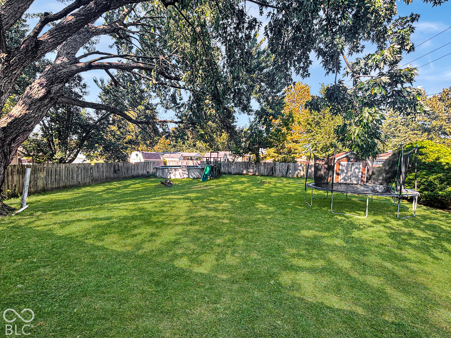 Virtually Altered - Spacious backyard featuring a manicured lawn, full-perimeter wood fencing, and mature canopy trees