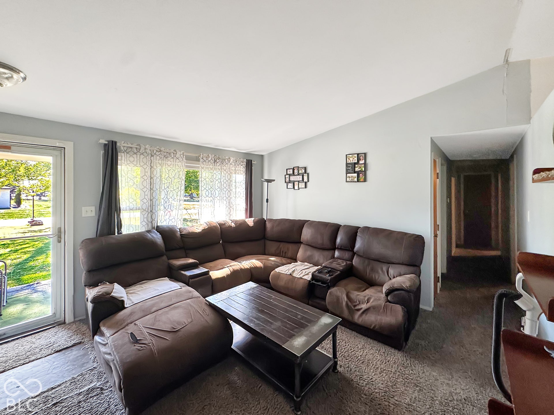 Vaulted ceiling featuring a glass-panel exterior door and a large multi-pane window assembly