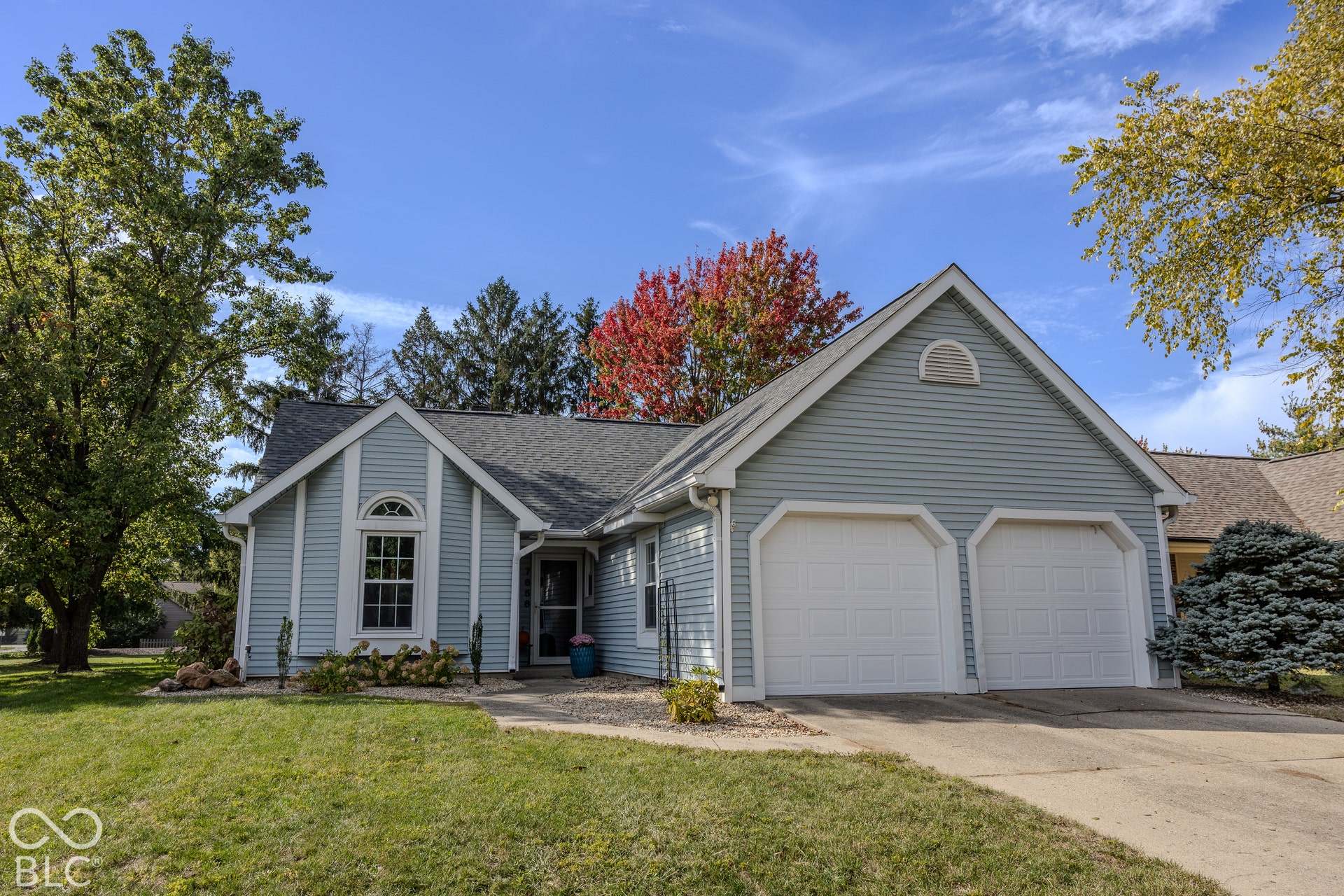 7656 Wickfield Way, Indianapolis, IN 46256 Single-story residence featuring light blue siding, a two-car garage, an arched window, and a paved driveway