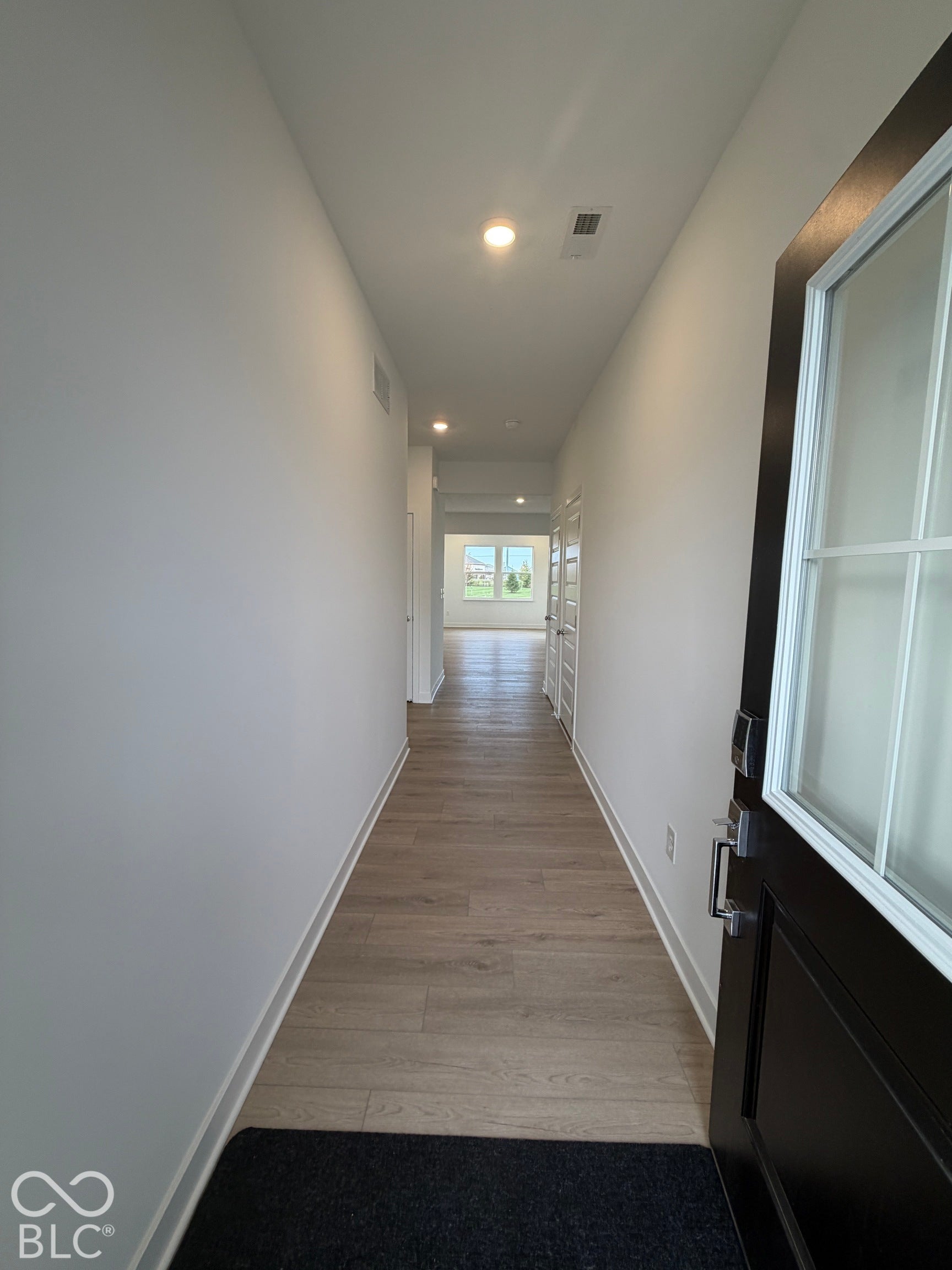 Entryway featuring a dark-finish door with glass panes, wood-finish flooring, recessed lighting, and interior doors with panel detailing