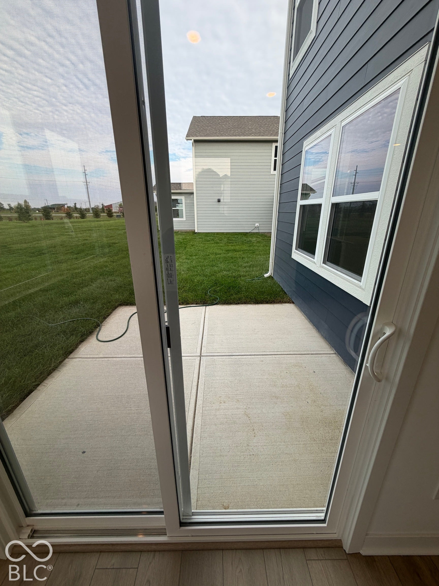 Concrete patio featuring horizontal lap siding, white-trimmed windows, and wood-finish flooring