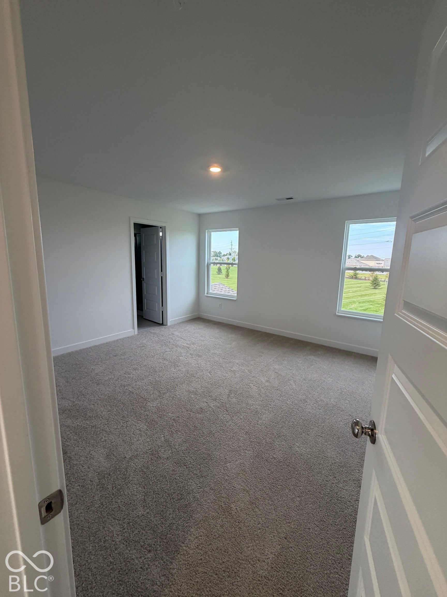 Interior room featuring neutral wall-to-wall carpeting, two windows, and overhead recessed lighting