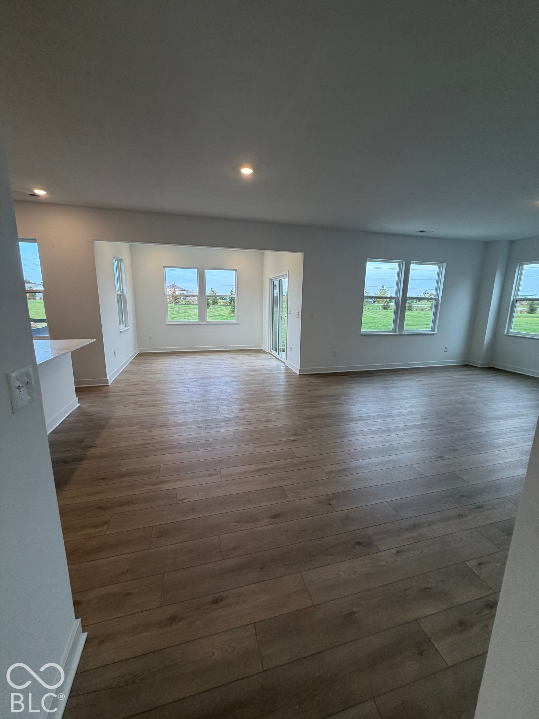 Open interior space featuring wood-finish flooring, recessed lighting, neutral wall paint, and multiple windows