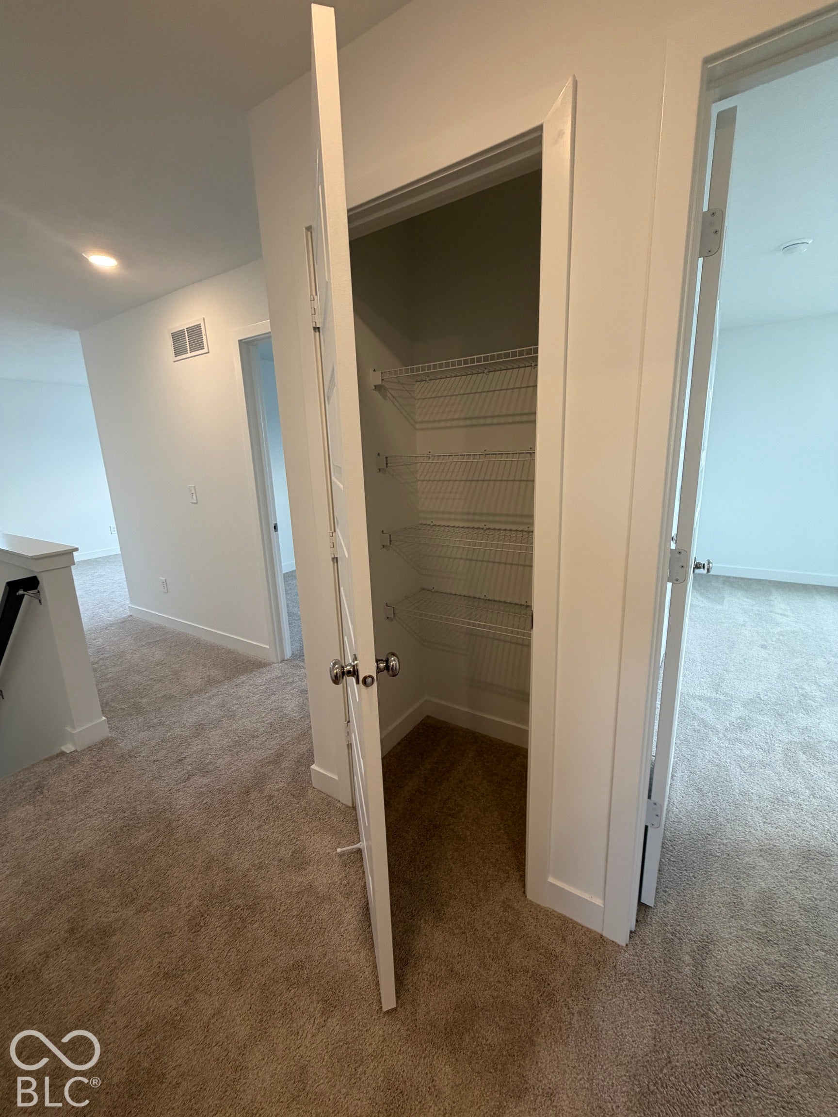 Interior storage closet featuring four tiers of wire shelving and a paneled door with polished hardware