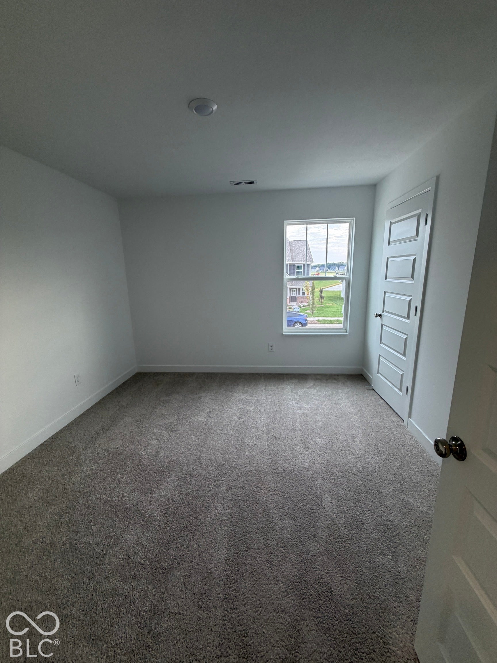 Neutral-toned wall-to-wall carpeting, single-hung window with muntin detailing, and five-panel interior door with matte black hardware