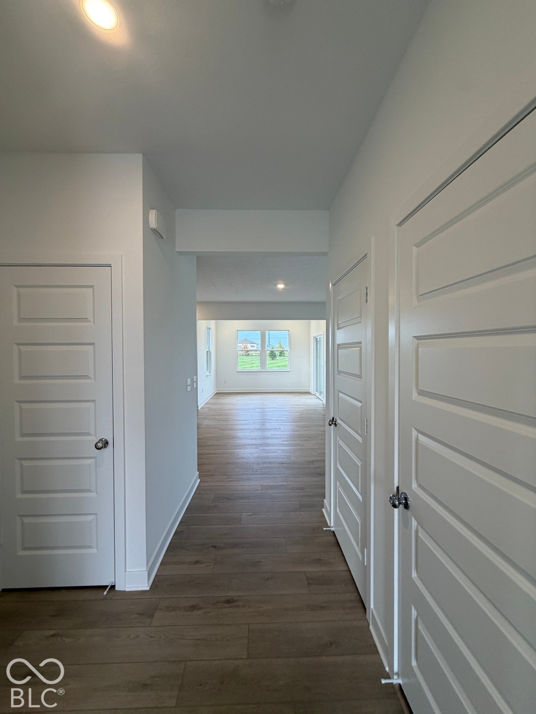 Interior hallway featuring wood-finish flooring, white five-panel doors, and recessed lighting