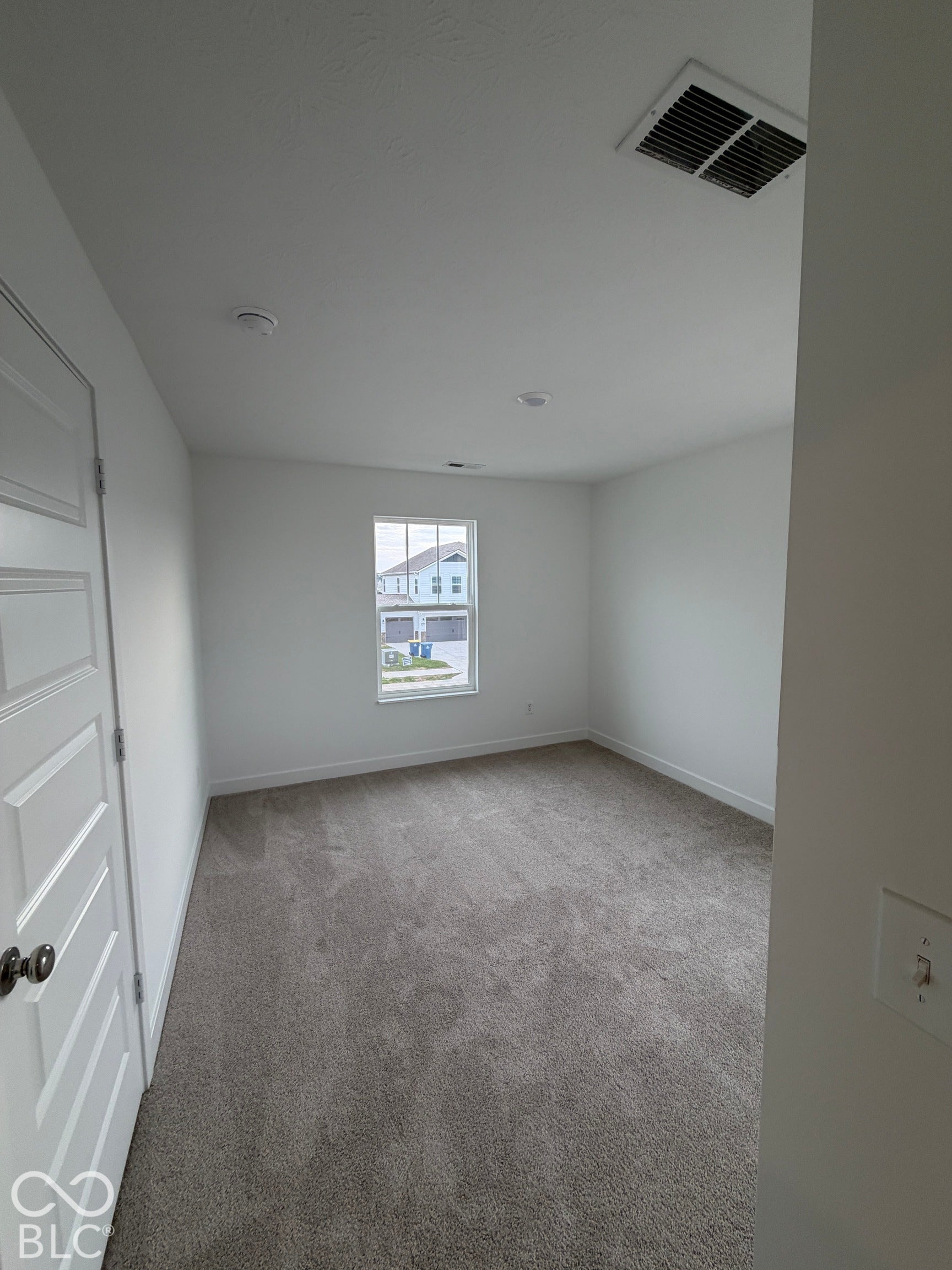 Interior space featuring neutral wall-to-wall carpeting, a single-hung window, and a multi-panel interior door