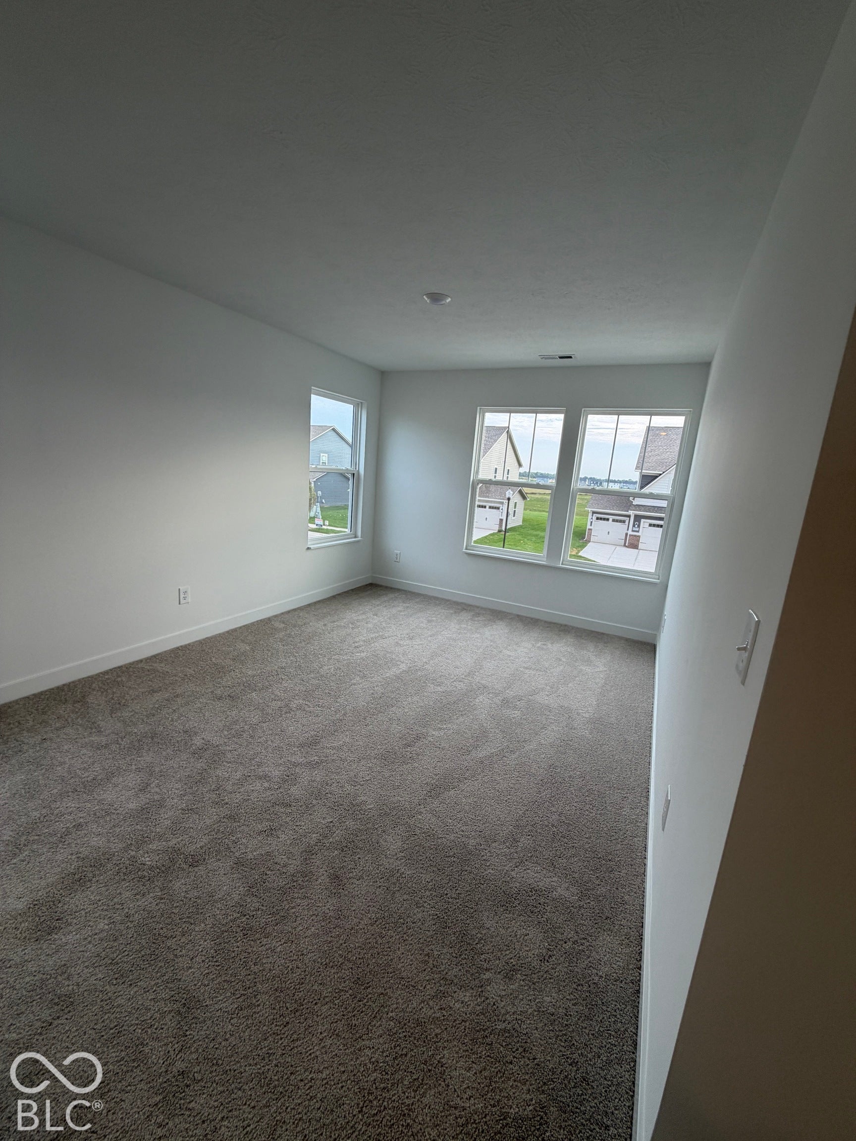 Neutral-toned interior space featuring plush carpeting, crisp white walls, and multi-pane windows with grid detailing