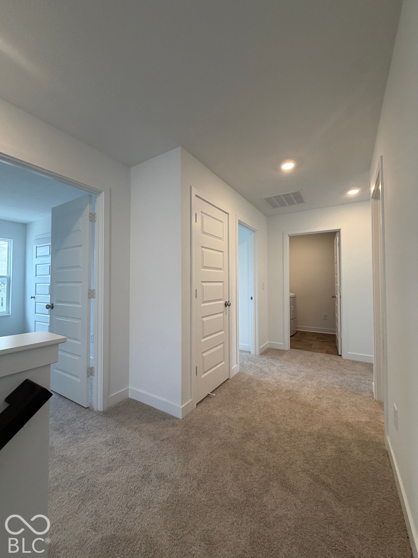 Neutral-toned carpeting, four-panel interior doors, and recessed ceiling lighting