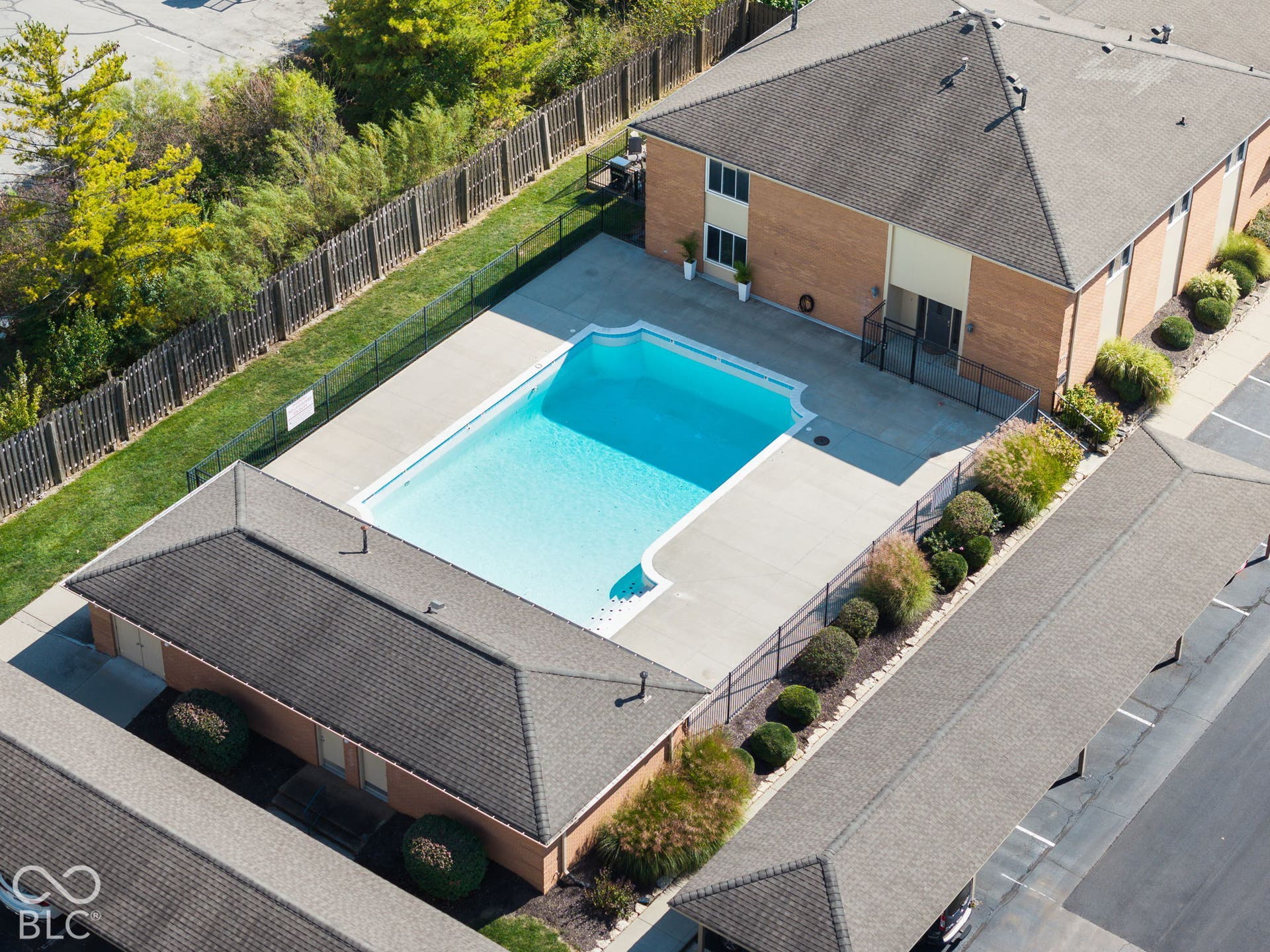 Outdoor swimming pool with concrete decking, perimeter fencing, and covered parking structures