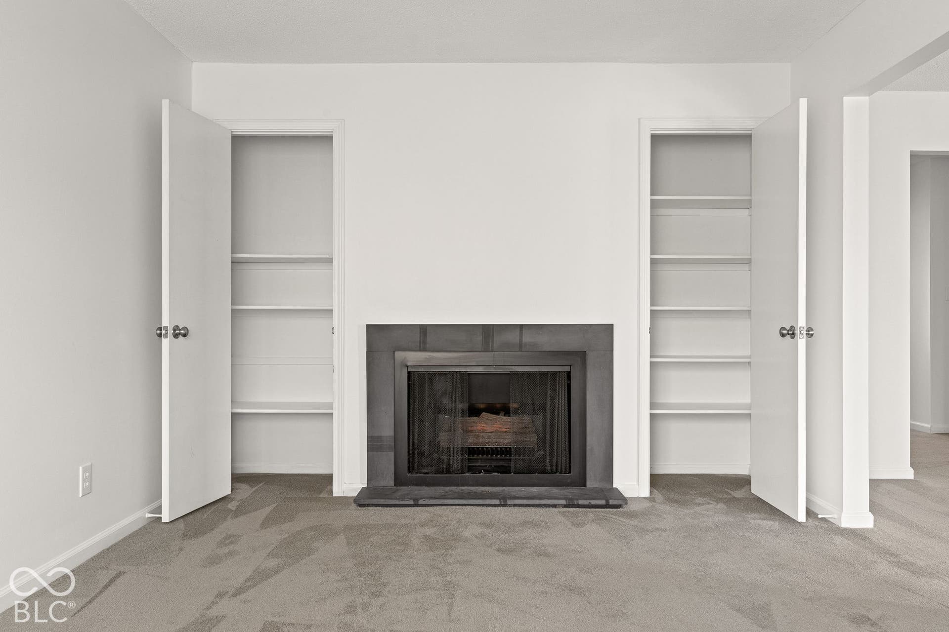 Fireplace with a charcoal-toned stone surround and hearth, flanked by dual recessed closets with built-in shelving