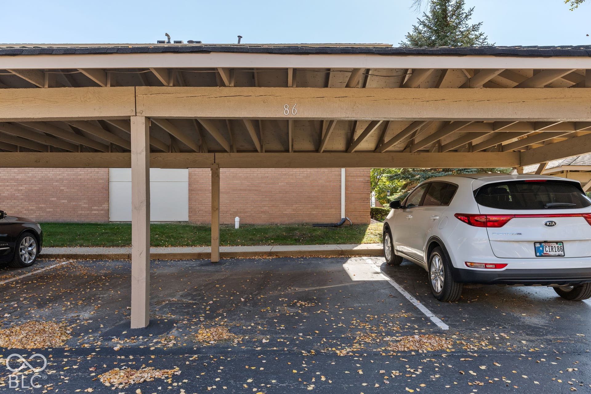 Covered parking structure featuring exposed timber framing and asphalt pavement