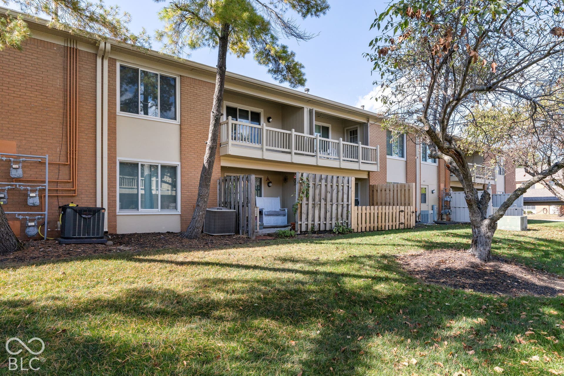 Multi-story brick exterior featuring second-level balcony railings and ground-level fenced patio enclosures