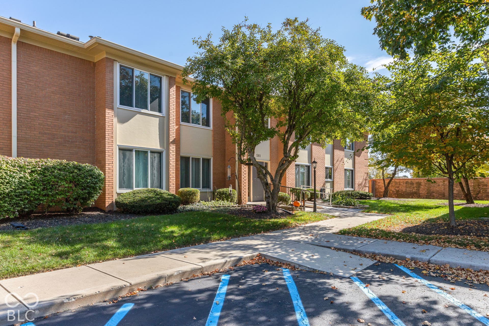 Multi-level brick exterior featuring expansive windows, mature landscaping, and concrete walkways