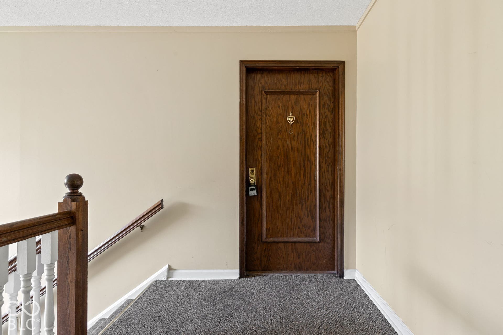 Solid wood-finish door with decorative brass-tone hardware, paired with a wooden handrail and white balustrade