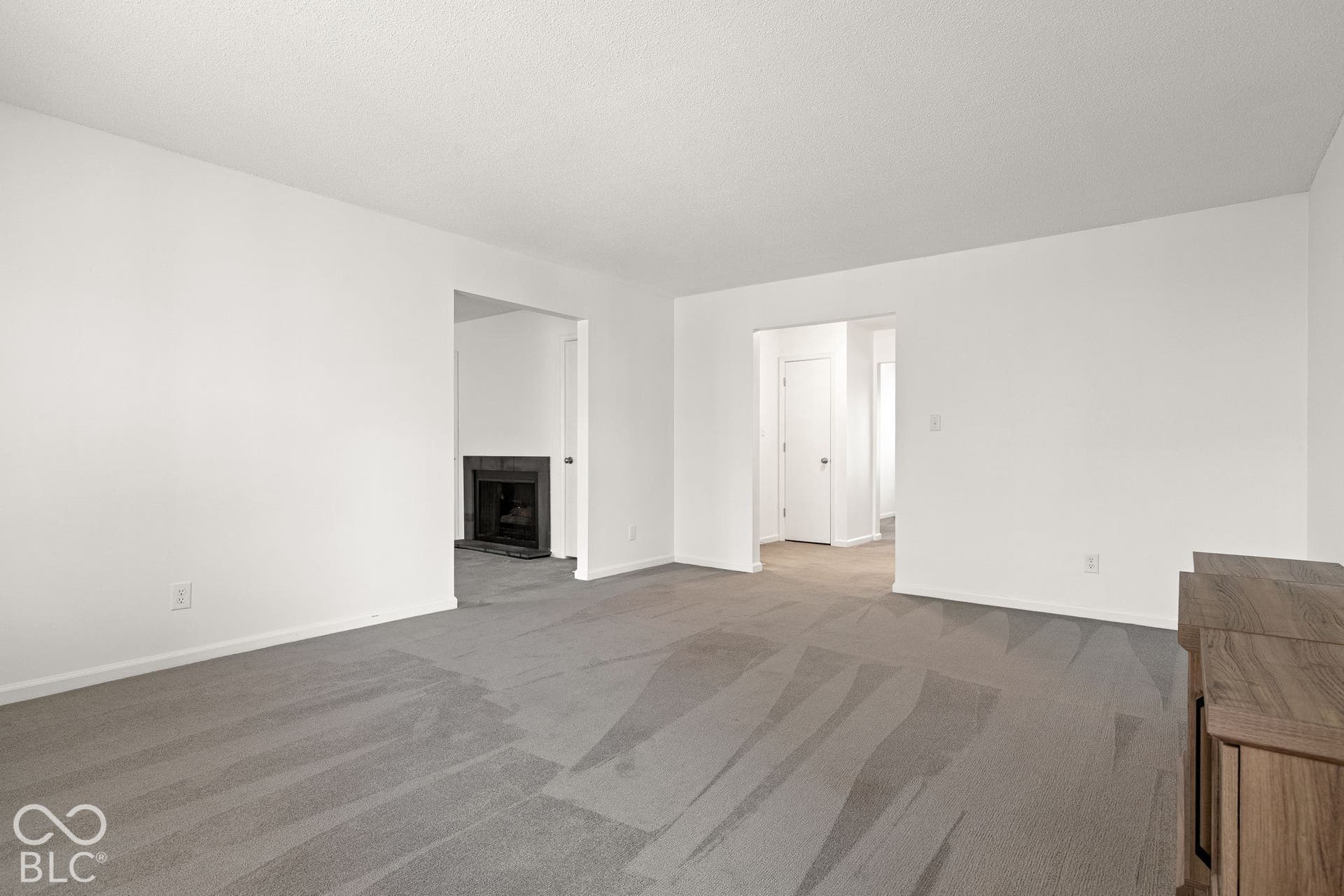 Neutral interior featuring wall-to-wall carpeting and a fireplace with a dark surround